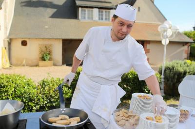 Chambre lumineuse avec lit double, décoration tropicale, plafond avec poutres apparentes et salle de bain attenante.