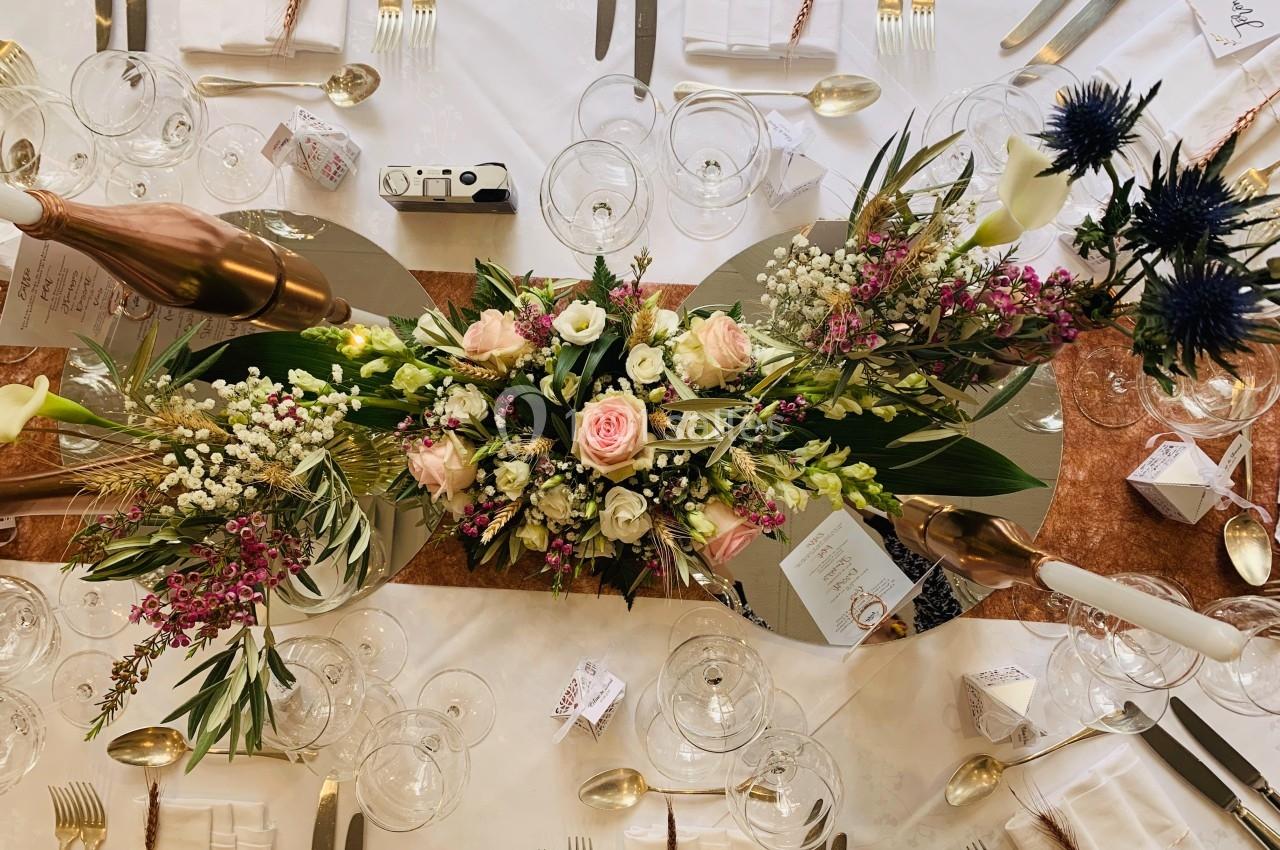 Table élégamment dressée avec des compositions florales colorées, couverts en métal et verres disposés harmonieusement.