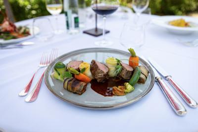 Chambre lumineuse avec lit double, décoration tropicale, plafond avec poutres apparentes et salle de bain attenante.