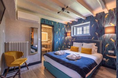 Chambre lumineuse avec lit double, décoration tropicale, plafond avec poutres apparentes et salle de bain attenante.