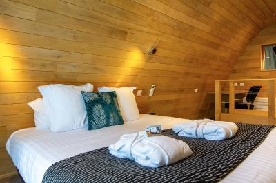 Chambre lumineuse avec lit double, décoration tropicale, plafond avec poutres apparentes et salle de bain attenante.