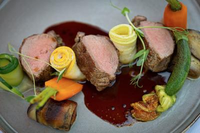 Chambre lumineuse avec lit double, décoration tropicale, plafond avec poutres apparentes et salle de bain attenante.