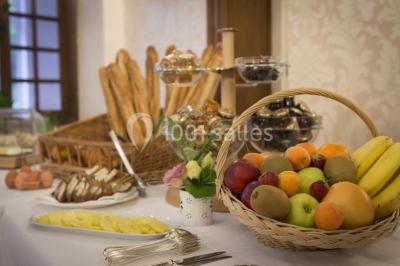 Chambre lumineuse avec lit double, décoration tropicale, plafond avec poutres apparentes et salle de bain attenante.