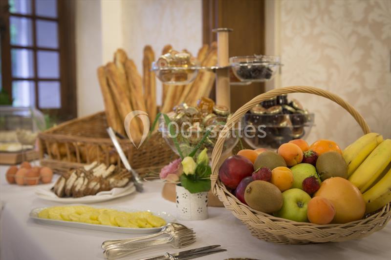 Table garnie de fruits, pains, viennoiseries et œufs, disposés pour un buffet dans un cadre chaleureux.