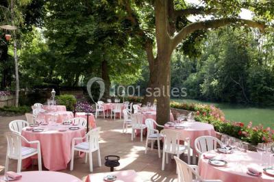 Salle de restaurant élégante avec nappes blanches, grandes fenêtres donnant sur un paysage verdoyant et décoration…