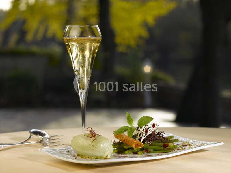 Assiette gastronomique avec légumes, herbes fraîches et mousse, accompagnée d'une flûte de champagne sur une table élégante.
