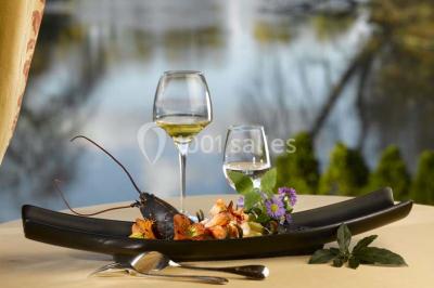 Salle de restaurant élégante avec nappes blanches, grandes fenêtres donnant sur un paysage verdoyant et décoration…