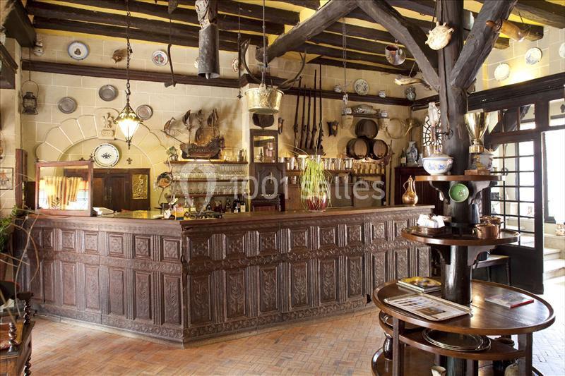 Intérieur d'un bar rustique avec comptoir en bois sculpté, décorations murales anciennes et ambiance traditionnelle.