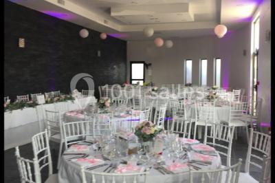 Cuisine professionnelle avec équipements en inox, fours encastrés, étagères murales et hotte d'extraction.