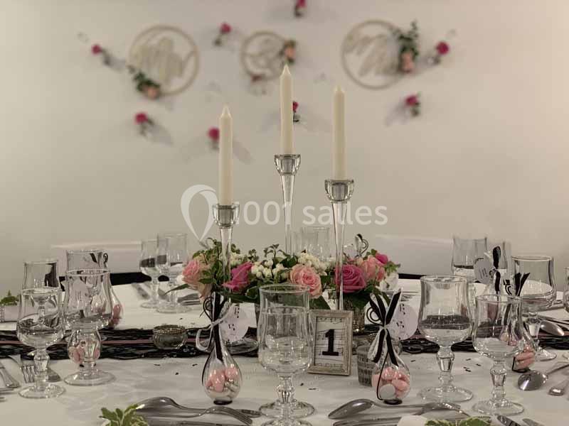 Table élégamment dressée avec bougies, fleurs roses et numérotation, décorée pour un événement ou un repas festif.