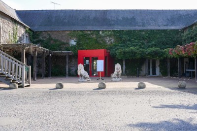 Bâtiment d'hôtel en pierre avec trois étoiles, entouré de végétation et d'une façade partiellement recouverte de lierre.