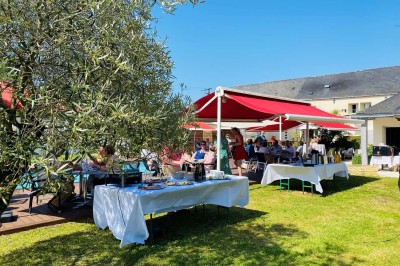 Bâtiment d'hôtel en pierre avec trois étoiles, entouré de végétation et d'une façade partiellement recouverte de lierre.