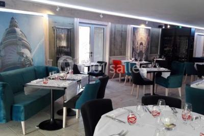 Piscine extérieure entourée de chaises longues et parasols, avec des bâtiments en arrière-plan sous un ciel dégagé.