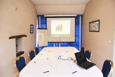 Piscine extérieure entourée de chaises longues et parasols, avec des bâtiments en arrière-plan sous un ciel dégagé.