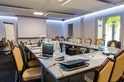 Piscine extérieure entourée de chaises longues et parasols, avec des bâtiments en arrière-plan sous un ciel dégagé.