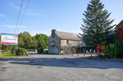 Piscine extérieure entourée de chaises longues et parasols, avec des bâtiments en arrière-plan sous un ciel dégagé.