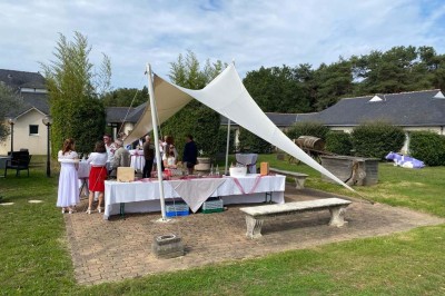 Piscine extérieure entourée de chaises longues et parasols, avec des bâtiments en arrière-plan sous un ciel dégagé.