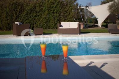 Piscine extérieure entourée de chaises longues et parasols, avec des bâtiments en arrière-plan sous un ciel dégagé.