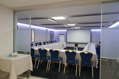 Piscine extérieure entourée de chaises longues et parasols, avec des bâtiments en arrière-plan sous un ciel dégagé.