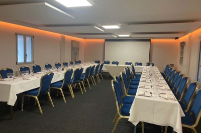 Piscine extérieure entourée de chaises longues et parasols, avec des bâtiments en arrière-plan sous un ciel dégagé.