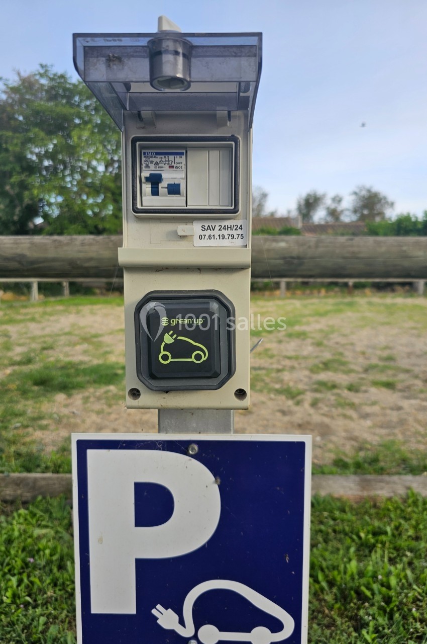 Borne de recharge électrique Green'up installée sur un parking extérieur, avec panneau signalant une place dédiée.