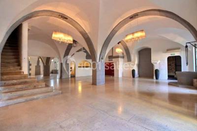 Salon lumineux avec fauteuils en cuir, table basse en bois, paniers en osier, escaliers et décorations florales.