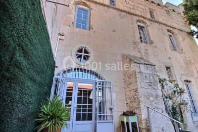 Salon lumineux avec fauteuils en cuir, table basse en bois, paniers en osier, escaliers et décorations florales.