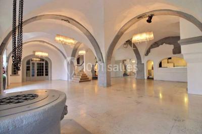 Salon lumineux avec fauteuils en cuir, table basse en bois, paniers en osier, escaliers et décorations florales.