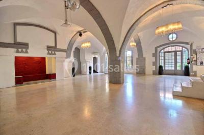 Salon lumineux avec fauteuils en cuir, table basse en bois, paniers en osier, escaliers et décorations florales.