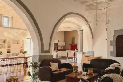 Salon lumineux avec fauteuils en cuir, table basse en bois, paniers en osier, escaliers et décorations florales.