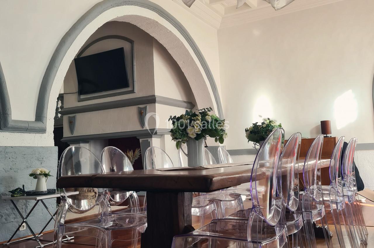Salle à manger lumineuse avec table en bois, chaises transparentes et lustre design sous un plafond à caissons.