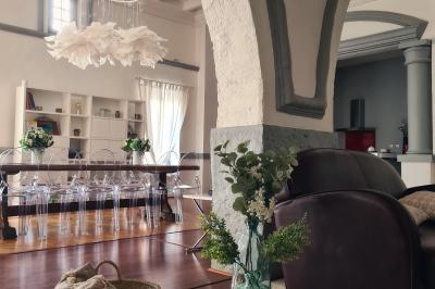 Salon lumineux avec fauteuils en cuir, table basse en bois, paniers en osier, escaliers et décorations florales.