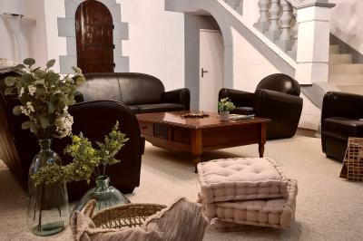 Salon lumineux avec fauteuils en cuir, table basse en bois, paniers en osier, escaliers et décorations florales.