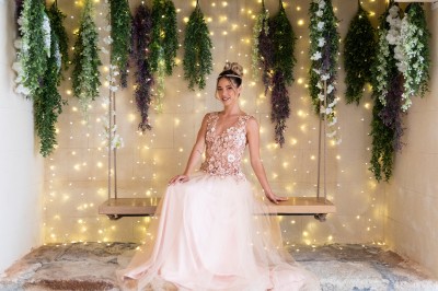 Femme en robe de mariée blanche avec dos en dentelle transparente, montant un escalier intérieur en pierre.