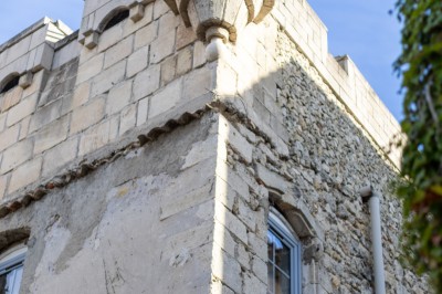 Femme en robe de mariée blanche avec dos en dentelle transparente, montant un escalier intérieur en pierre.