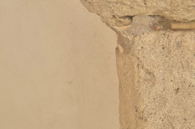 Femme en robe de mariée blanche avec dos en dentelle transparente, montant un escalier intérieur en pierre.