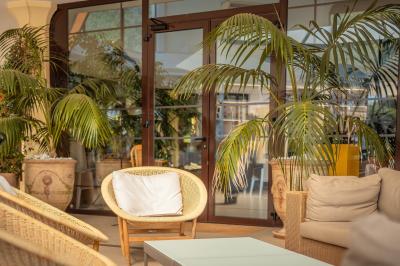 Salle lumineuse avec de grandes baies vitrées, mobilier en cuir et bois, et une horloge murale décorative.