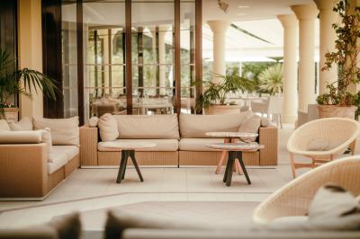 Salle lumineuse avec de grandes baies vitrées, mobilier en cuir et bois, et une horloge murale décorative.