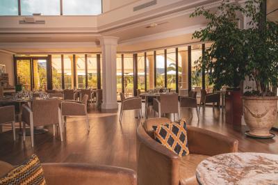 Salle lumineuse avec de grandes baies vitrées, mobilier en cuir et bois, et une horloge murale décorative.