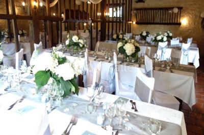 Chambre lumineuse avec deux lits simples, sol en carrelage, plafond en bois, et vue sur un jardin depuis une porte ouverte.