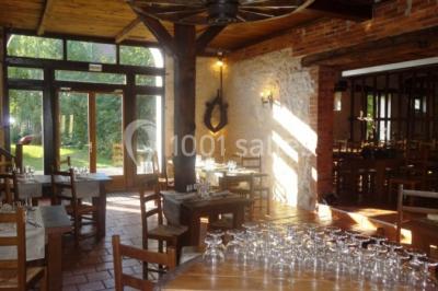 Chambre lumineuse avec deux lits simples, sol en carrelage, plafond en bois, et vue sur un jardin depuis une porte ouverte.