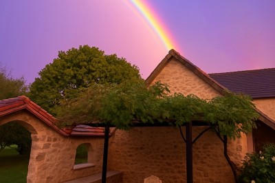 Façade d'une maison à colombages avec jardinières fleuries et un jardin verdoyant au premier plan.