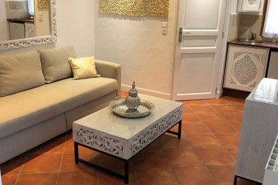 Façade d'une maison à colombages avec jardinières fleuries et un jardin verdoyant au premier plan.