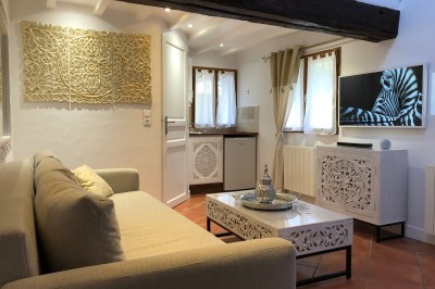 Façade d'une maison à colombages avec jardinières fleuries et un jardin verdoyant au premier plan.