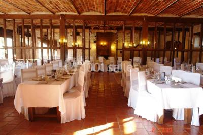 Chambre lumineuse avec deux lits simples, sol en carrelage, plafond en bois, et vue sur un jardin depuis une porte ouverte.