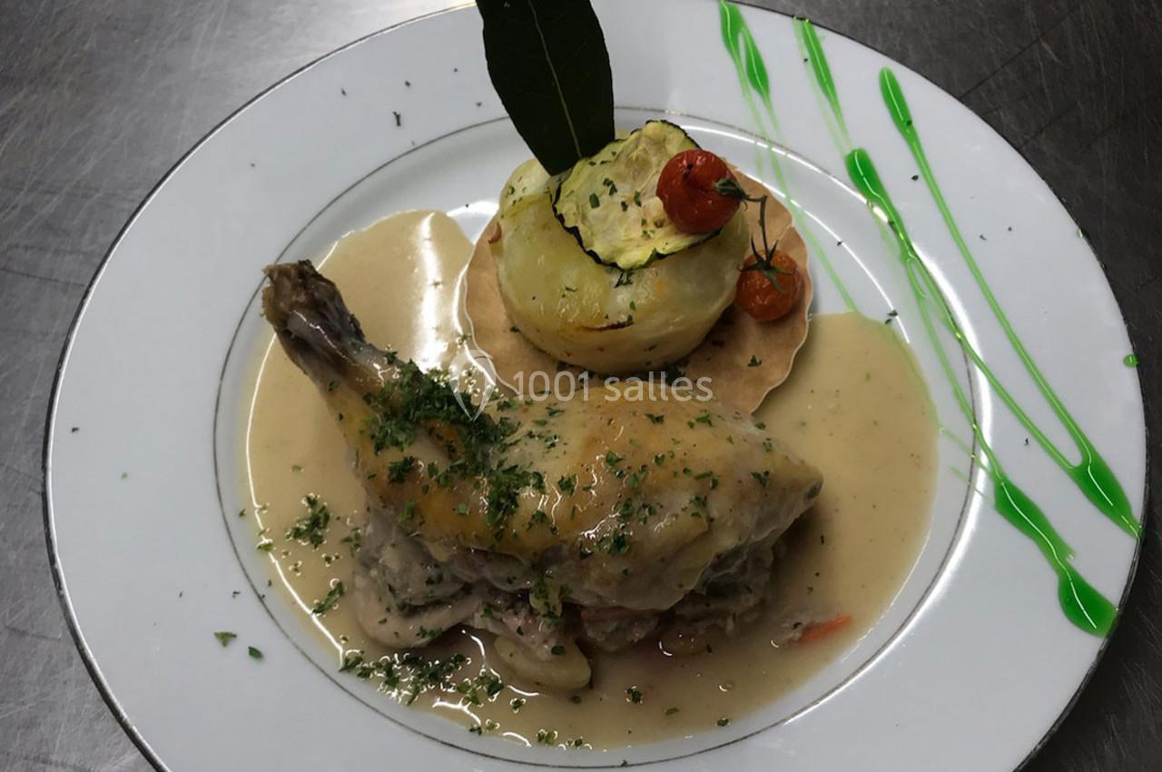 Assiette de cuisse de volaille en sauce, accompagnée d'un gratin de légumes et décorée de tomates cerises et d'une feuille…