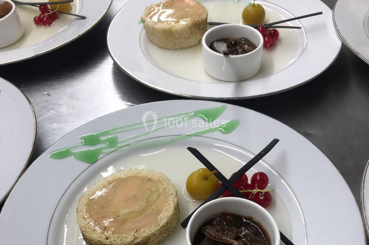 Assiette gastronomique avec foie gras, confit d'oignons, groseilles, sauce verte décorative et garnitures sucrées.