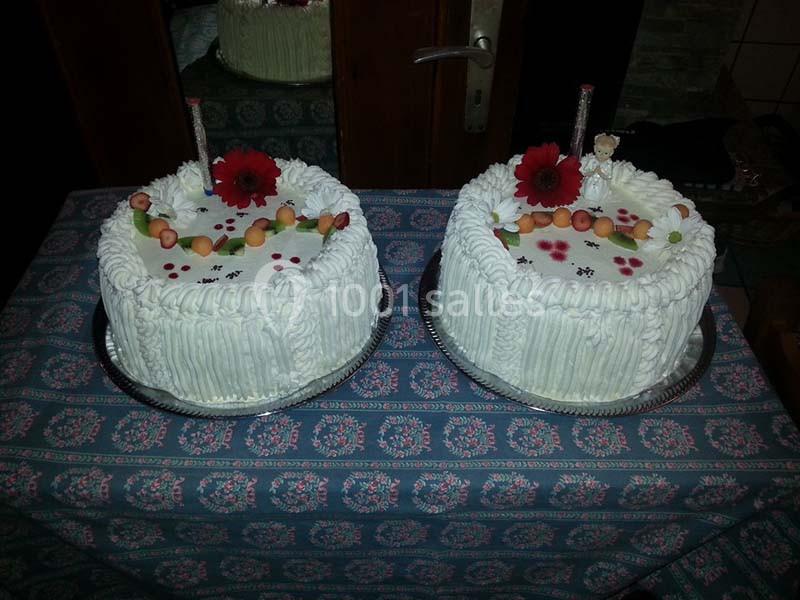 Deux gâteaux décorés de crème blanche, fraises, fleurs rouges et figurines, posés sur une nappe à motifs.
