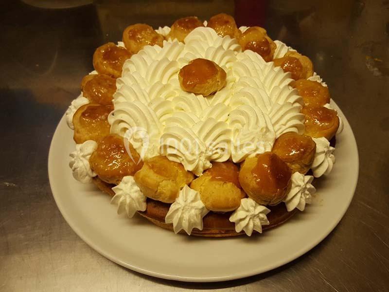 Gâteau Saint-Honoré avec choux caramélisés, crème chantilly et pâte feuilletée, présenté sur une assiette blanche.