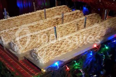Grandes bûches pâtissières décorées de glaçage blanc, présentées sur une table ornée de guirlandes lumineuses et de…